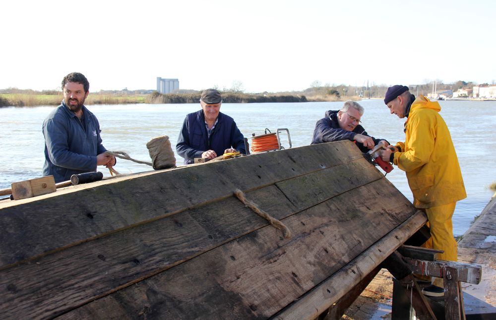 Calfatage de la coque à l'aide de filasse appliquée en force entre les pièces de bois qui seront au contact de l'eau en frappant avec un maillet sur un fer à calfat. La filasse est ensuite protégée par un enduit de goudron.