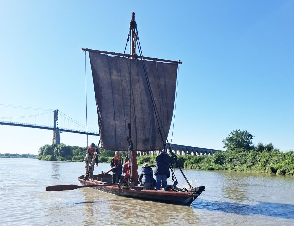 La Mona avec la voile, les rames et le courant descendant en aval du pont suspendu.